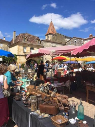 a group of people standing around a market with tables at Monpazier Situation idéale Lumineux Terrasse in Monpazier