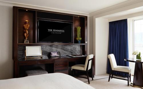 a bedroom with a desk with a television on a wall at The Peninsula Chicago in Chicago