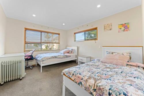 a bedroom with two beds and a desk and two windows at Not usually available – Lucky U! in Auckland