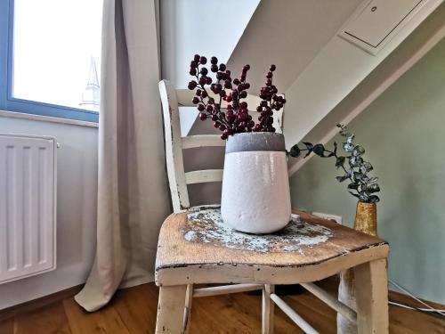 a white vase sitting on a chair with flowers at BohnApartments Bauhaus - absolutes Zentrum - Terrasse - Vollausstattung - WLAN in Weimar