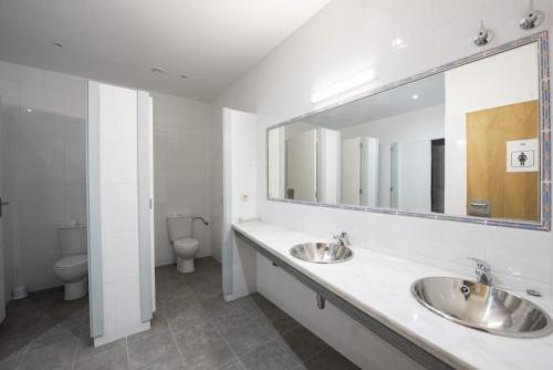 a bathroom with two sinks and a mirror and a toilet at Vila Vilariño Albergue Hotel & Restaurante in Ourense