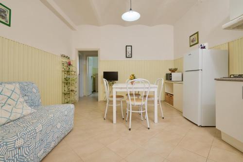 a living room with a table and a kitchen with a refrigerator at Mare Etrusco 4 in Populonia