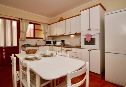 eine Küche mit einem weißen Tisch und einem weißen Kühlschrank in der Unterkunft Angela Beach Place in Vila Baleira