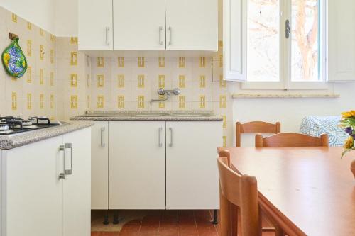 a kitchen with white cabinets and a wooden table at Mare Etrusco 2 in Populonia