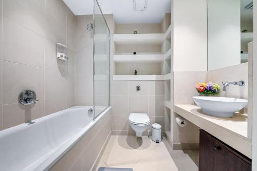 a bathroom with a tub and a toilet and a sink at Londwell, Canary Wharf River Thames Balcony Suite in London