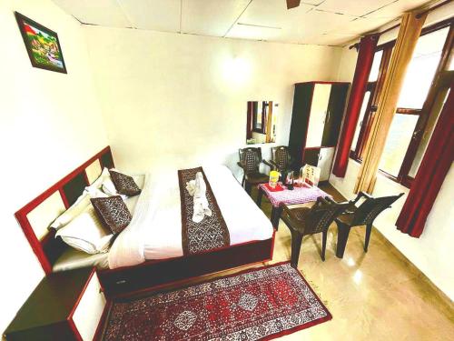 a bedroom with a bed and a table and chairs at The Lake Cottage by VRB Hotels in Dharamshala
