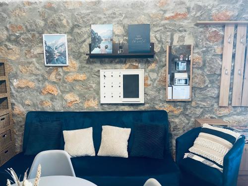 ein blaues Sofa in einem Zimmer mit einer Steinmauer in der Unterkunft Kuća za odmor “Dida” in Stinica