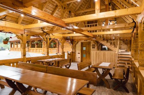 a restaurant with wooden ceilings and tables and benches at Valea Legendelor in Grădiştea de Munte