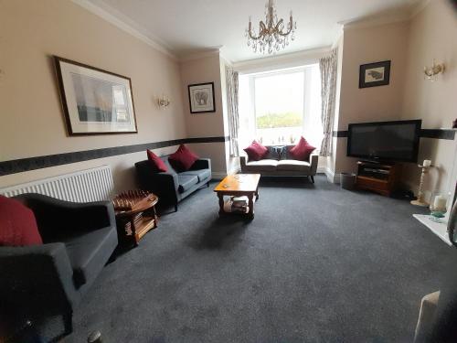 a living room with couches and a flat screen tv at The Rosscourt Hotel in Bournemouth