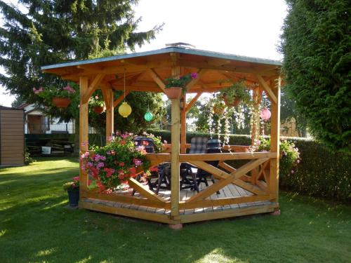 Gotthun的住宿－Ferienwohnung unweit der Müritz，庭院里种满鲜花的木制凉亭