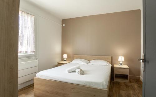 een slaapkamer met een wit bed met 2 tafels en 2 lampen bij L'orchidée Altéa in Annecy