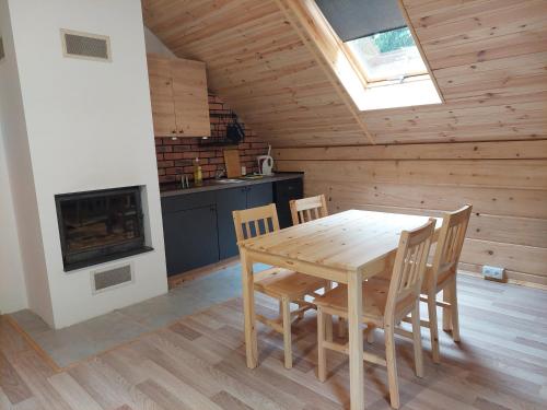 a wooden table and chairs in a room with a fireplace at Willa Ozark in Zawóz