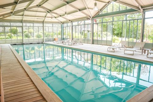 une grande piscine avec un grand plafond en verre dans l'établissement Le Clos de Grâce, à Honfleur