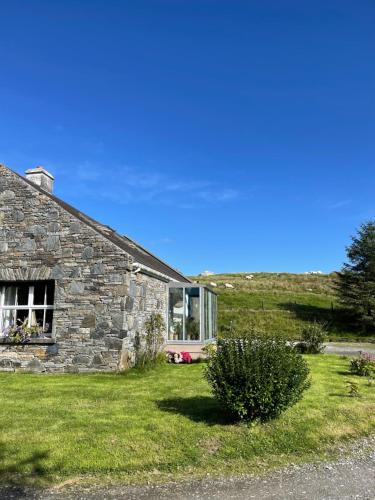 ein Steinhaus mit einem Fenster und grünem Gras in der Unterkunft Bed & Breakfast - Shanakeever Farm in Clifden