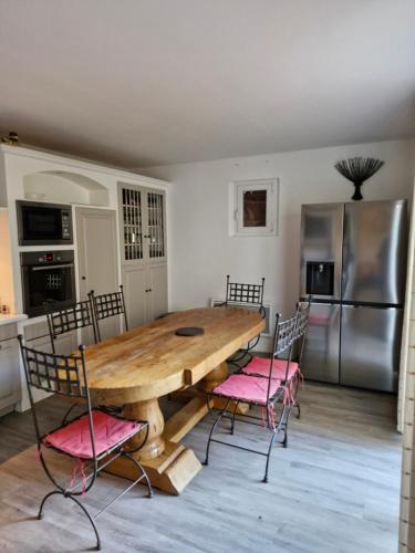 une cuisine avec une table en bois et des chaises roses dans l'établissement Maison avec piscine privée, sauna et activités - Rendez-vous en Provence, à Althen-des-Paluds