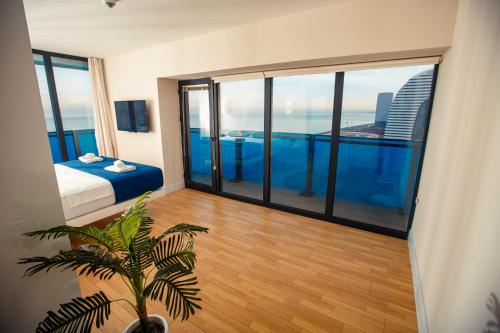 a bedroom with a bed and large glass windows at Aparthotel orbi with Sea View in Batumi