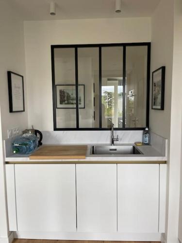 - un comptoir de cuisine avec un évier et un miroir dans l'établissement Bel appart proche Paris, 3 chambres, Balcon & Parc, à Suresnes