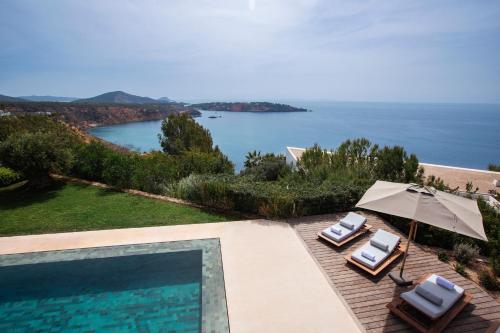 a swimming pool with two lawn chairs and an umbrella at Villa Turquesa in Es Cubells
