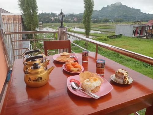 een tafel met borden ontbijtproducten op een balkon bij The Twins Homestay in Rantepao