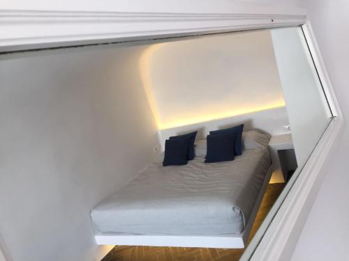 a small bed in a small room with blue pillows at Altana Cliffside Villas in Imerovigli
