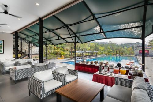 an outdoor patio with a swimming pool with chairs and a table at Pelangi Park Hotel & Resort in Pasirkuda