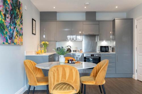 a kitchen with a table and chairs in a kitchen at Elliot Oliver - Stylish 2 Bedroom Apartment With Parking In The Docks in Gloucester
