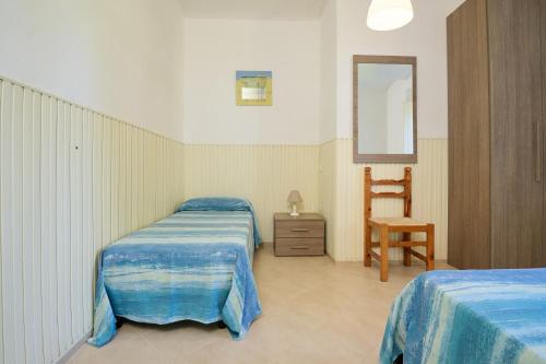 1 Schlafzimmer mit 2 Betten, einem Stuhl und einem Spiegel in der Unterkunft Mare Etrusco 8 in Populonia