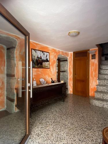 pasillo con paredes de color naranja y puerta de madera en B&B Pudzones, en Santu Lussurgiu