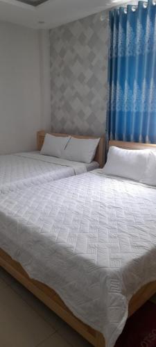 een slaapkamer met 2 bedden en een blauw gordijn bij Nhà Nghỉ Kim Cương in Rach Gia