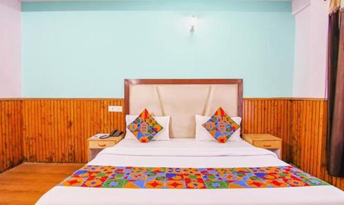 a bedroom with a large bed with a colorful comforter at FabHotel Kundan Inn in Manāli