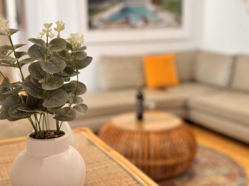 a white vase with a plant on a table in a living room at Gold Coast-Miami Mid-Century Beach Home With Pool in Gold Coast