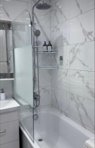 y baño blanco con ducha y bañera. en A cosy apartment en Osh