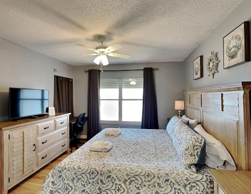 a bedroom with a bed with a ceiling fan and a television at Sea Winds 602 in Ormond Beach