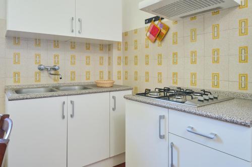 a kitchen with white cabinets and a sink at Mare Etrusco 5 in Populonia