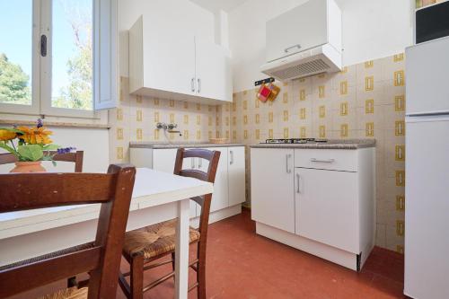 a kitchen with white cabinets and a table and chairs at Mare Etrusco 5 in Populonia