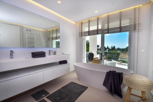 La salle de bains blanche est pourvue d'une baignoire et d'une fenêtre. dans l'établissement Exquisite and Modern villa near beach with Heated pool!, à Marbella