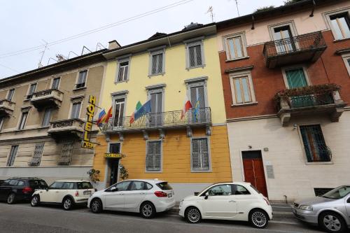 un gruppo di auto parcheggiate di fronte a un edificio di Hotel Piola a Milano