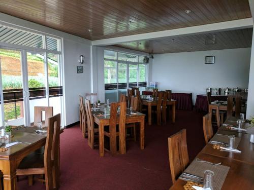 een restaurant met houten tafels, stoelen en ramen bij New Ashley Resorts (PVT) LTD in Nuwara Eliya