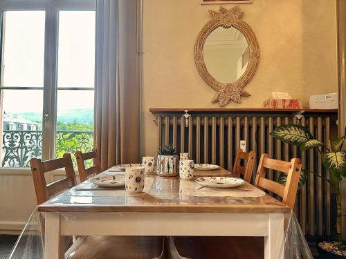 - une table à manger avec des chaises et un miroir dans l'établissement Carla’s Résidences Studio Hyper Centre, à Aix-les-Bains