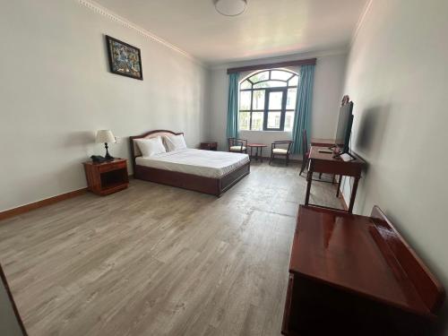 a bedroom with a bed and a desk and a window at NGOC THU HOTEL in Soc Trang