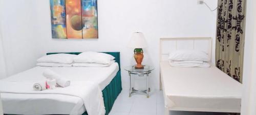 duas camas com lençóis brancos e um candeeiro sobre uma mesa em Balai Ti Somera em Cabugao