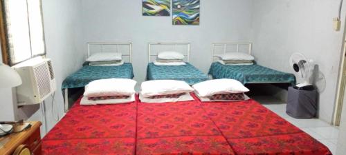 um quarto com três camas e um tapete vermelho em Balai Ti Somera em Cabugao