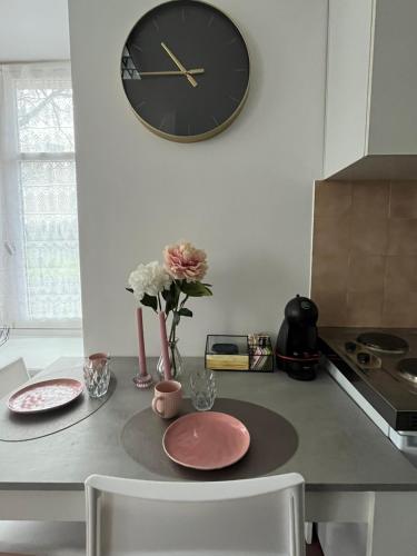 une cuisine avec une horloge sur le mur et une table dans l'établissement Résidence du lévezou, à Salmiech