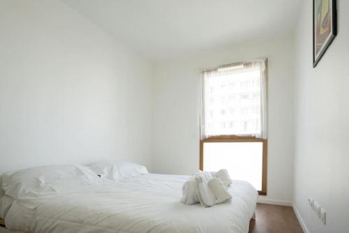 une chambre blanche avec un lit avec des serviettes dessus dans l'établissement Spacieux appartement - Stade de France, à Saint-Denis