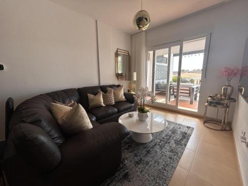 ein Wohnzimmer mit einem Ledersofa und einem Tisch in der Unterkunft Impeccable 2-Bed Apartment in Alhama de Murcia in Alhama de Murcia