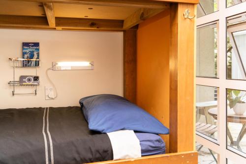 Ce lit se trouve dans une petite chambre dotée d'une fenêtre. dans l'établissement Haka Lodge Auckland, à Auckland