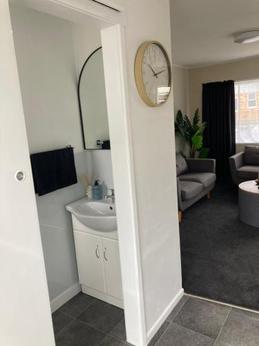 a bathroom with a sink and a clock on the wall at 108 by the Lake in Taupo