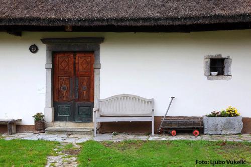 una casa blanca con un banco y una puerta en Dormouse House in Slovenia en Grahovo