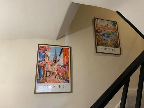 two pictures hanging on a wall next to a staircase at Chester City Centre townhouse in Chester