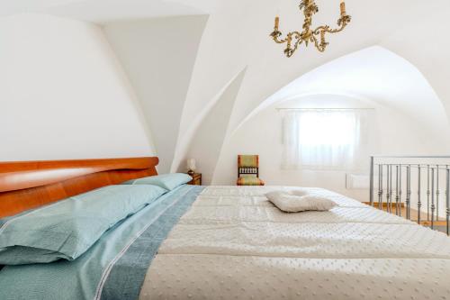 a white bedroom with a large bed with a chandelier at Casa Beatrice in Caprarica di Lecce